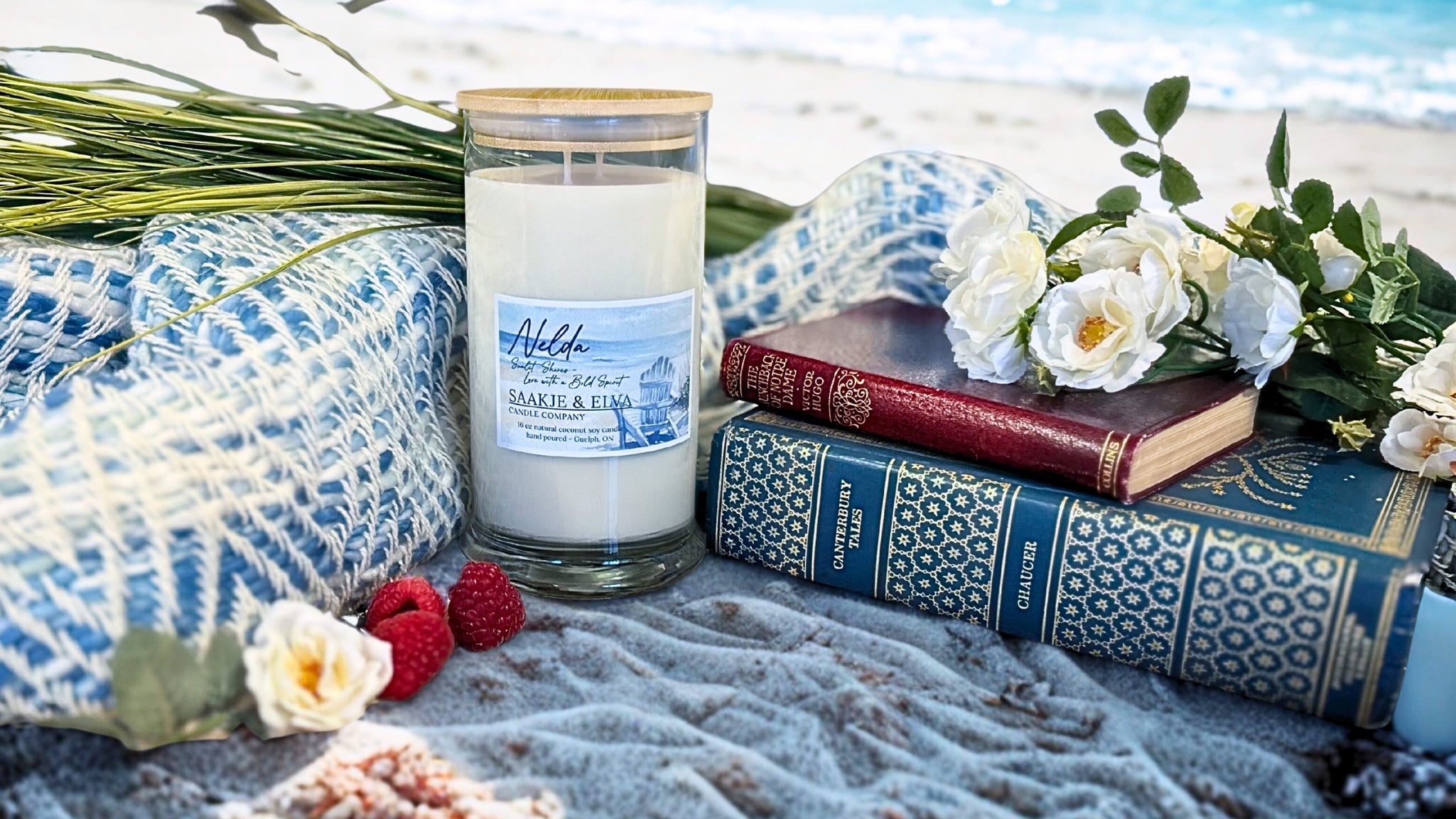Candle with a label, books, and flowers on a beach setting