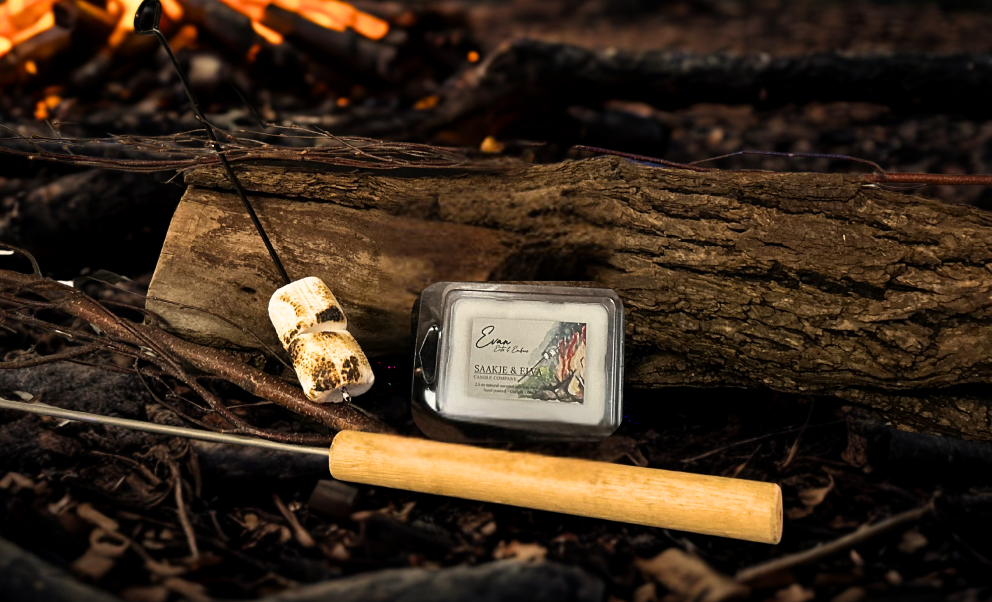 Fire starter kit with matches and lighter on a log in front of a fire beside candle