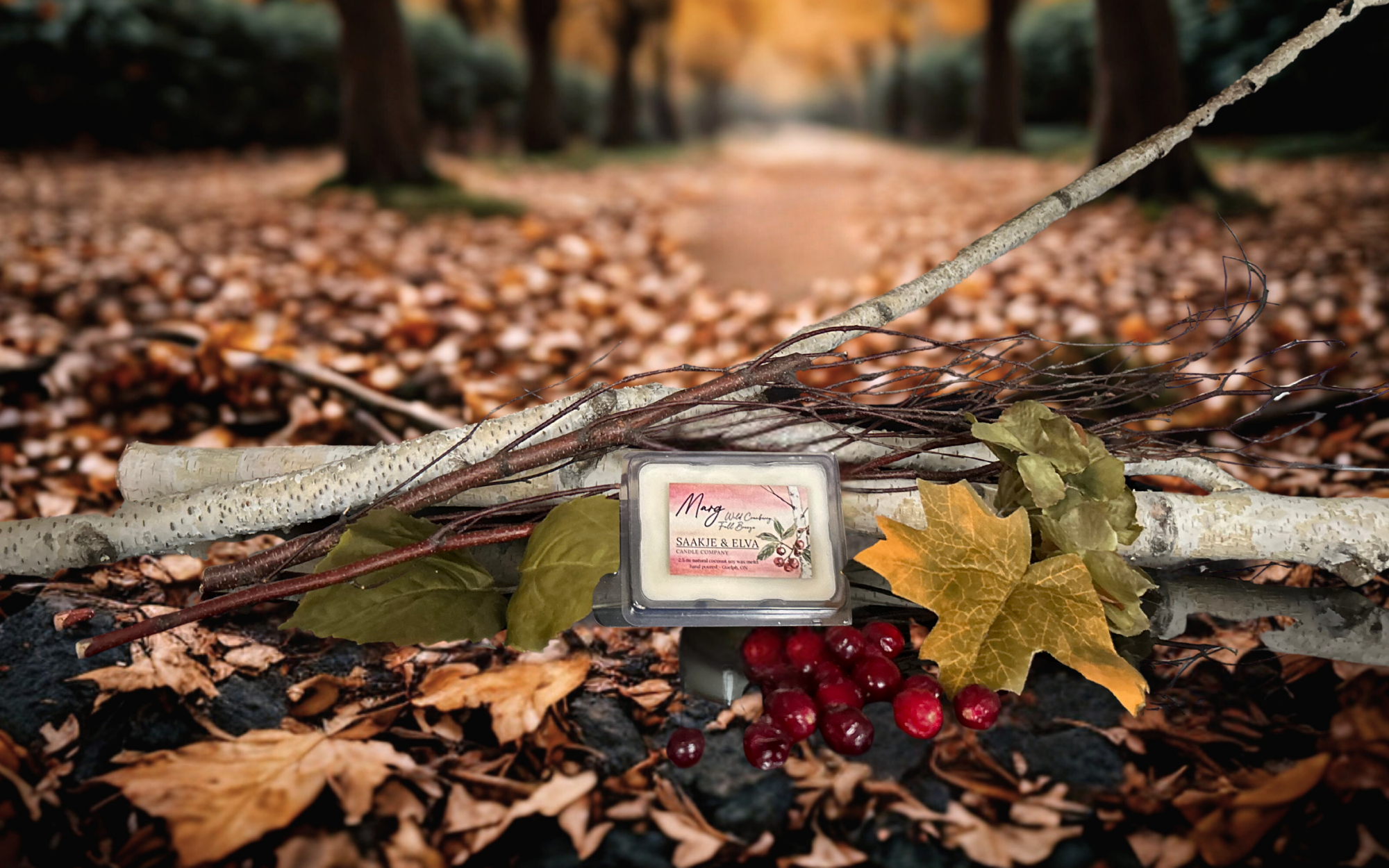 Small candle with a label on a branch surrounded by autumn leaves and berries.